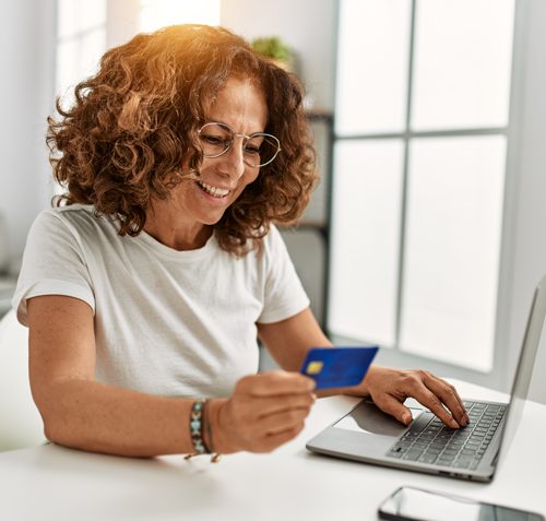 Middle age hispanic woman using laptop holding credit card home